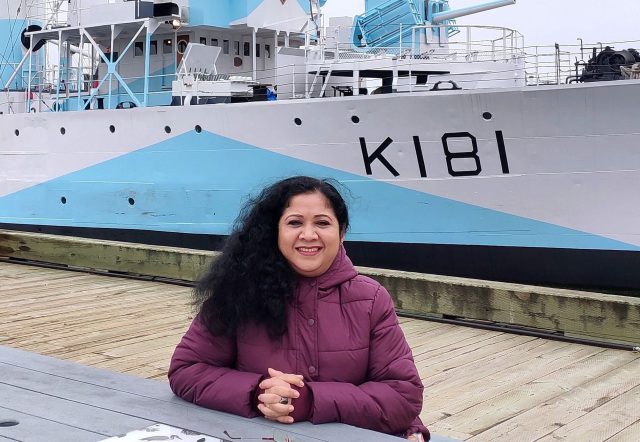 Editor sitting beside a ship overlooking the sea.