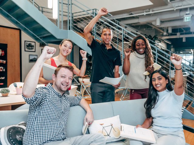 Capturing the essence of unity and shared values, this image portrays a group of individuals putting up their fists, echoing the principles highlighted in the article on building winning teams.