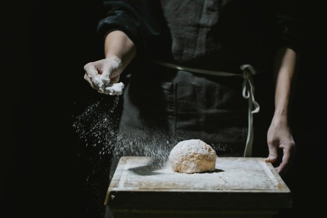 Entrepreneurial creativity in action: A chef sprinkling flour on dough, embodying the delicate balance between productivity and the artistry of meaningful work.