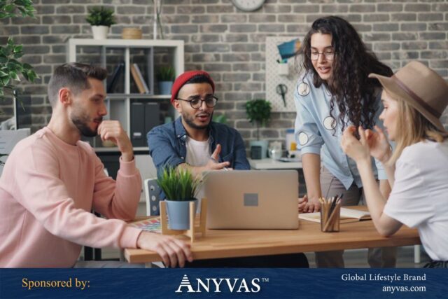 Group of young professionals collaborating around a laptop in a modern office setting, representing teamwork and innovation in business. Sponsored by Anyvas, a global lifestyle brand.