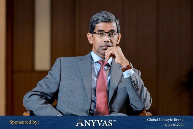 Arfan Ali sitting on a chair in formal attire, representing Zaytoon Business Solutions, with news sponsorship by Anyvas.