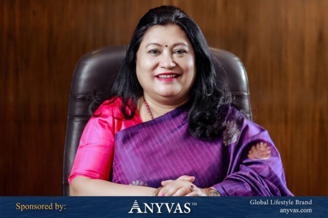 Rupali Chowdhury seated gracefully in a chair, representing leadership and poise, with the news proudly sponsored by global lifestyle brand ANYVAS.