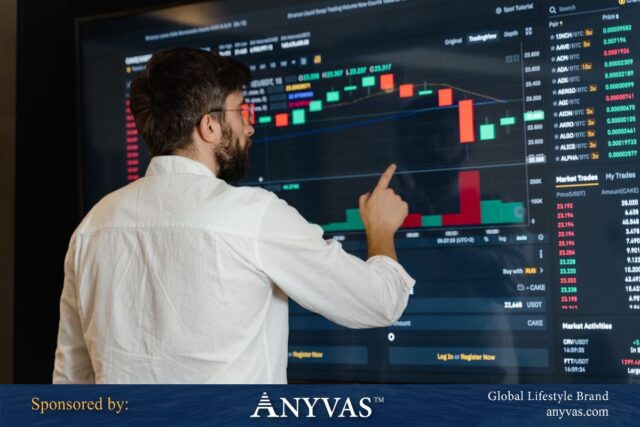 A man in a white shirt analyzing a large digital stock market chart display with various candlestick graphs and trading data.