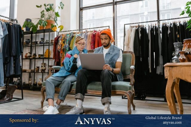 Two professional team members discussing a project, one holding a tablet and the other pointing at a laptop. Sponsored by Anyvas.